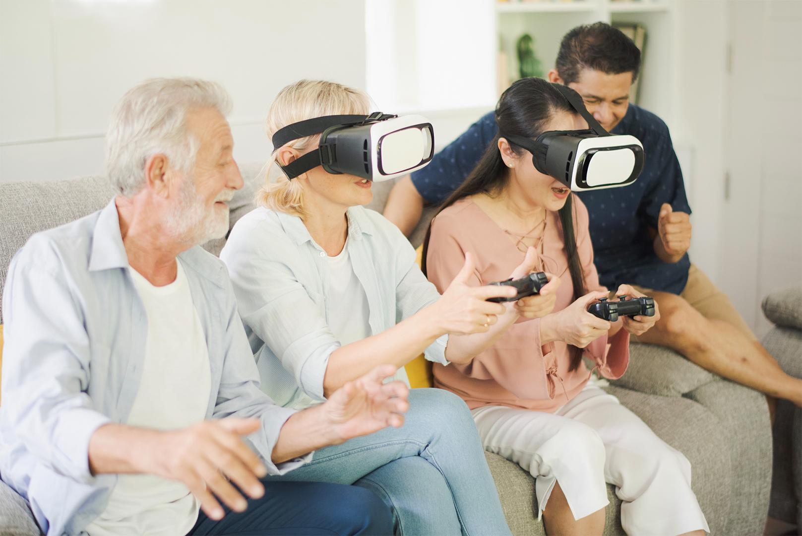Personengruppe auf Sofa spielen mit VR-Brillen an einer Konsole